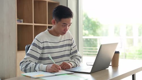Man Working at Desk with Laptop and Notebook