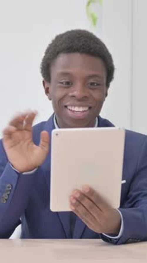 Young man in suit jacket video chatting on tablet