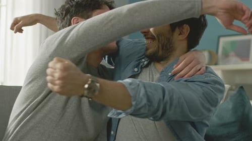 Young Men Celebrate Friendship with an Embrace on Couch