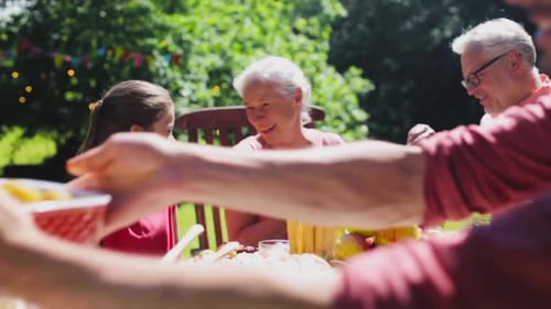Family Gathered Around Table Eating in Garden