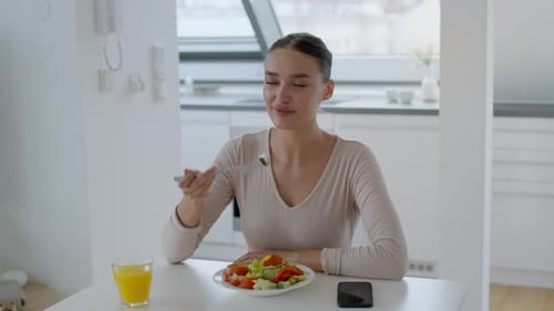 Attractive Woman Enjoying Healthy Salad in Bright Kitchen