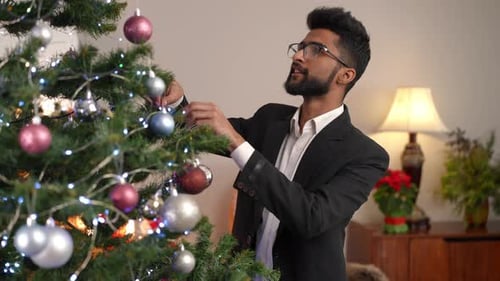 Young Adult Decorating Christmas Tree at Home