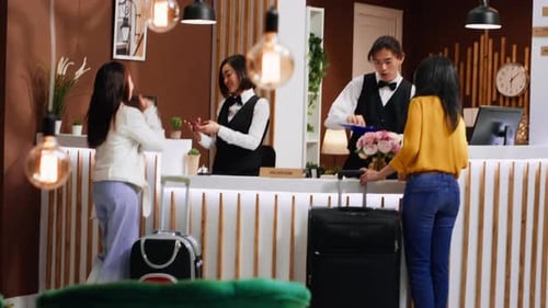 Guests Checking Into Hotel At Reception Desk