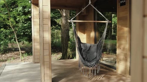 Empty Hammock Swinging on Cabin Porch in Nature