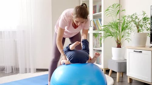 Woman Exercising with Child on Yoga Ball