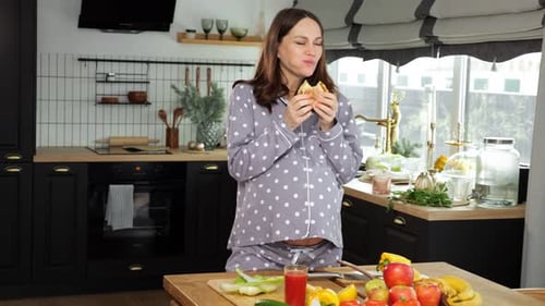Pregnant Woman Enjoying Sandwich in Bright Kitchen