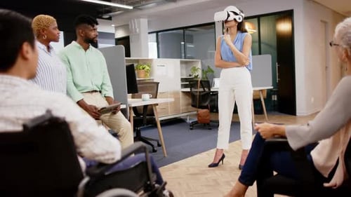 Using VR headset, woman leading diverse team meeting in modern office setting