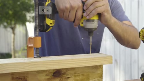 Close up shot of carpenter woodworker using power tools to screw 2x4 planks and plywood board togeth