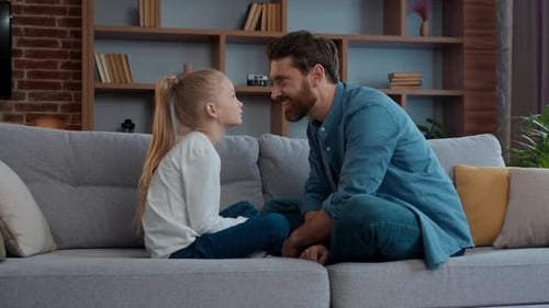 Father and Daughter Talking on Sofa in Living Room