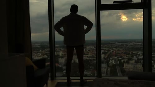 Man Silhouette Stands Contemplative in High Rise at Sunset