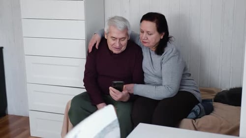 Mature Couple Watching Smartphone Together Indoors