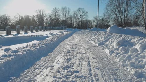 Low angle upward panning footage of a pedestrian white snow covered road during winter sunny day.