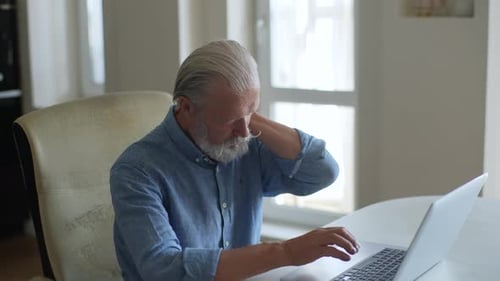 Senior Man Massaging Neck While Using Laptop