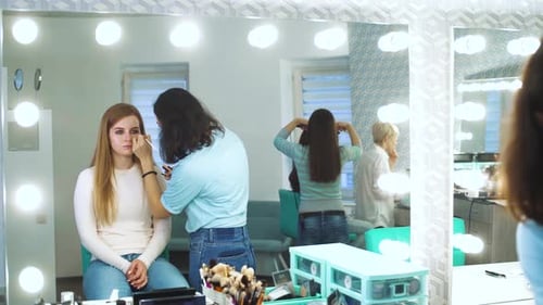 Makeup Artist Applying Makeup in Bright Studio