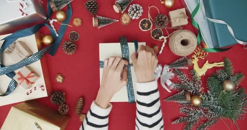 Top view of girl hands unpacking present gift box winter christmas decorations on red background.