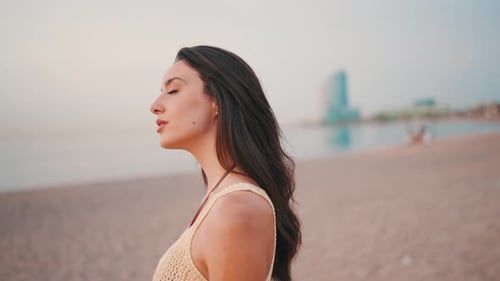 Profile Beautiful woman with long hair walks along the beach on seascape background
