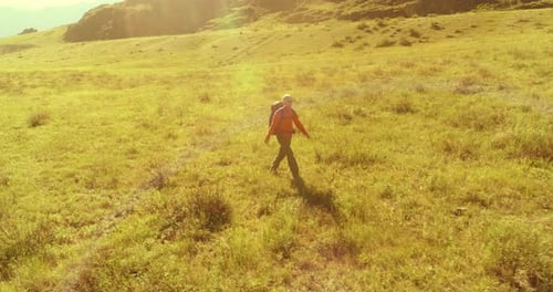Flight Over Backpack Hiking Tourist Walking Across Green Mountain Field Huge Rural Valley at Summer