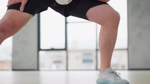 Trainer Performing Side Lunge Stretch Warm Exercise In Modern Gym With Windows