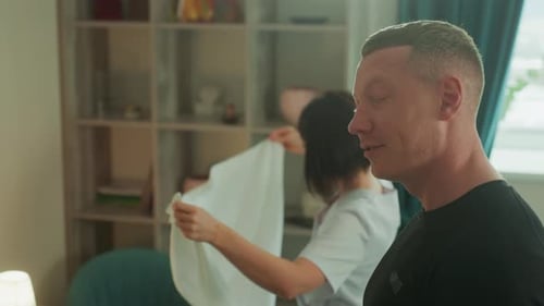 Man Smiling as Woman Folds Clothes in Apartment