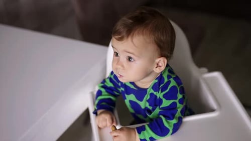 Adorable Baby Being Fed in High Chair