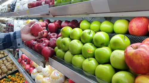 Un homme choisit une pomme au marché d'un supermarché de fruits et légumes