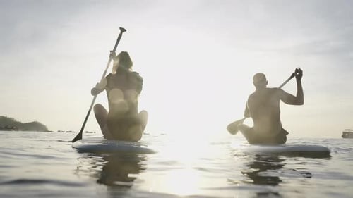 Couple Sitting on Their Paddle Boards Paddling at Sunset in Thailand
