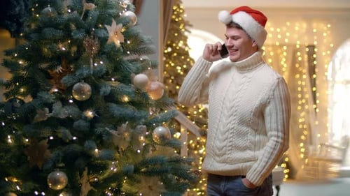 Man Talking on Cellphone Beside Christmas Tree