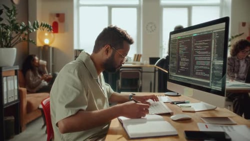 Programmer on Coding on Computer and Taking Notes at Office Workplace