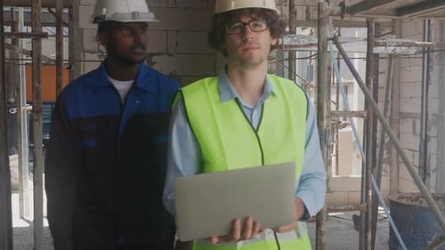Team architect two young man discussing and looking laptop for inspection construction site.
