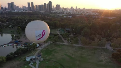 Aerial Shot Of Hot Air Balloon Descending Over Yarkon Park Against Sky In City