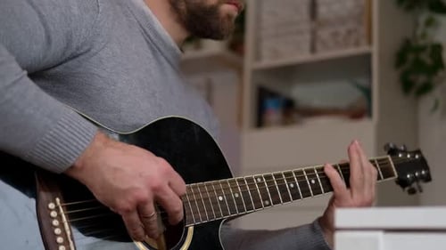 Man Playing Acoustic Guitar Indoors in Daylight