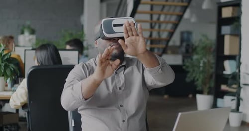 African American Man Using Virtual Reality Glasses in Office Moving Hands Enjoying Device During
