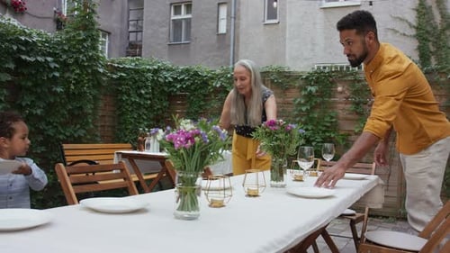 Family preparing table in backyard garden for party