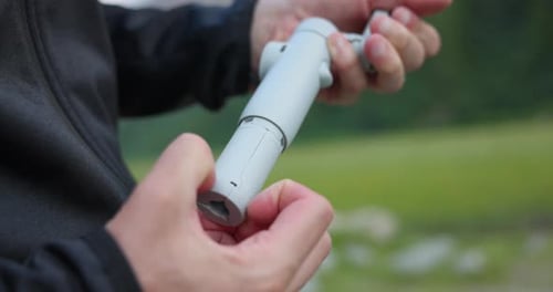 Hand Pulling Out Tripod Stand Of Insta360 Flow Pro AI Tracking Stabilizer. closeup shot