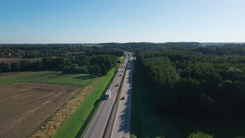 Aerial view of highway with cars passing through forest and fields