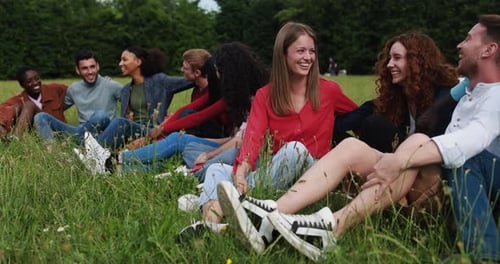 Group of Multiethnic Friends Having Fun Sitting on Grass Outdoor African