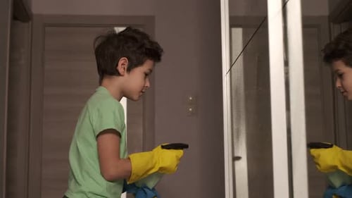 Boy with Inspiration Cleans the House Washes the Mirror with a Spray and a Sponge the Mantesori