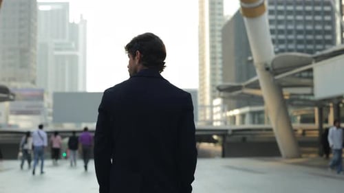 Un homme d'affaires traverse la place urbaine d'un immeuble moderne du centre-ville avec vue arrière