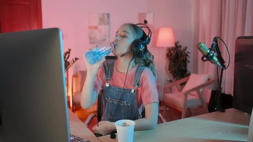 Teenage Girl Watching Stream of Video Game on Computer at Night