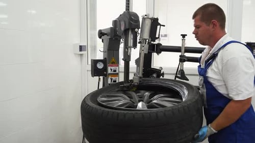 Auto Mechanic Uses Tire Changer to Swap Seasonal Wheels in Garage Professional in Workwear Aligns