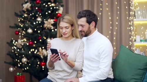 Couple Enjoys Christmas Cheer Using Smartphone