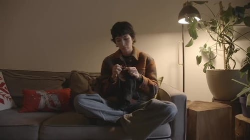 Moderne kaukasische Frau sitzt zu Hause beim Stricken auf der Couch