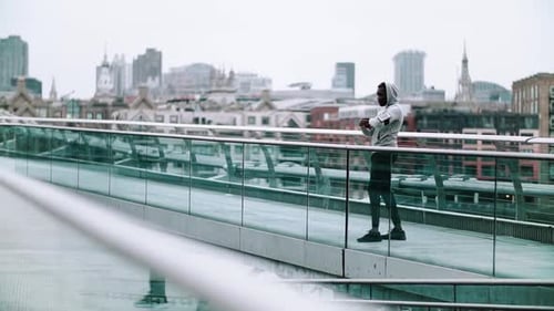 Black Man Runner With Smart Watch And Smartphone On The Bridge In A City, Resting. Slow Motion
