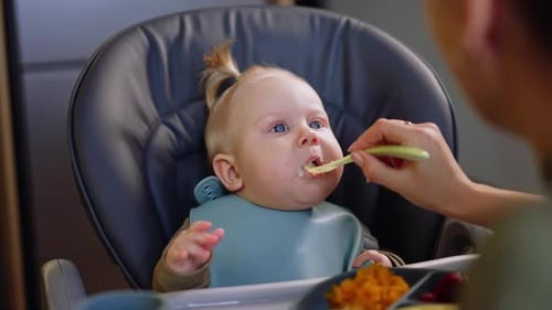 Baby Receiving Food from Spoon in High Chair
