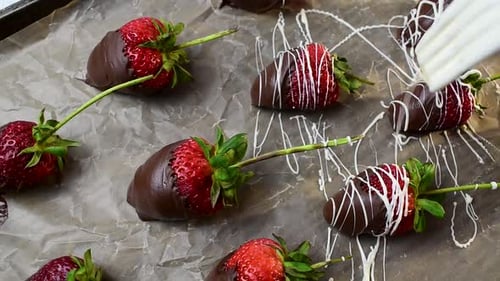drizzling tray of strawberries dipped in chocolate with white chocolate