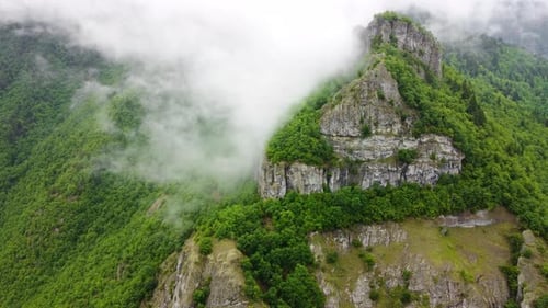 Voando através das nuvens acima da floresta montanhosa com vista aérea superior da névoa matinal