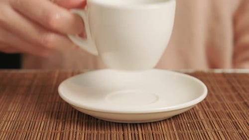 Hand of a Woman Drinking Coffee with a White Ceramic Cup in a Cafe