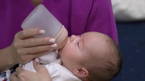 Caring Woman Feeds Infant with Bottle