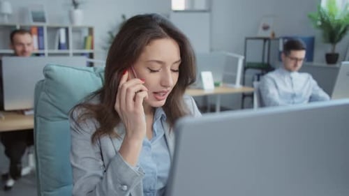 Woman talking on phone working on computer