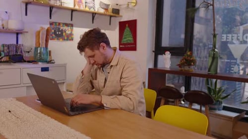 Jovem profissional estressado trabalhando remotamente em seu laptop experimentando emoções